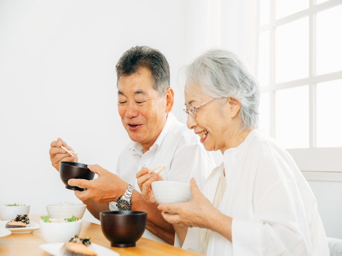 食卓で汁物を手に笑顔を見せるご利用者様
